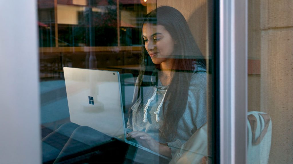 Eine Schülerin der Oberstufe sitzt mit einem Surface auf dem Boden Eine Schülerin sitzt mit einem Surface auf den Boden