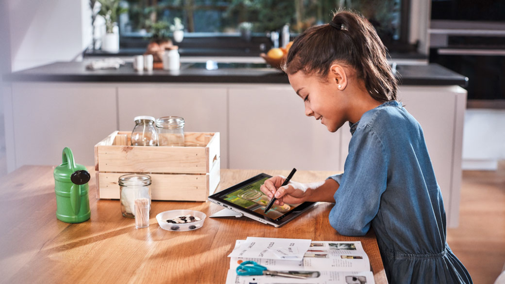 Ein junges Mädchen lernt in einer lichtdurchfluteten Küche an einem Tablet. Ein junges Mädchen lernt in der Küche an einem Tablet.