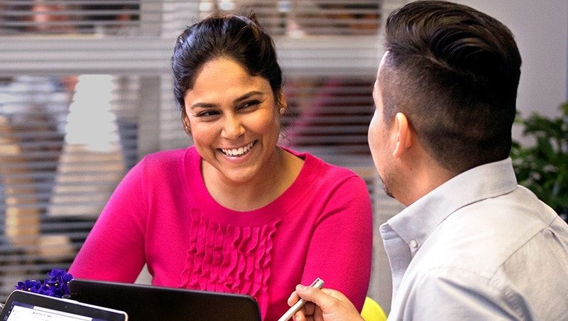 Lehrkräfte unterhalten sich sitzend an einem Tisch mit verschiedenen Devices.