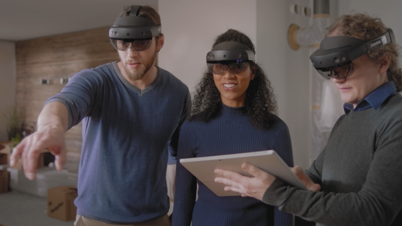 Drei Personen mit einer Microsoft HoloLens 2 schauen sich in einem virtuellen Raum um.