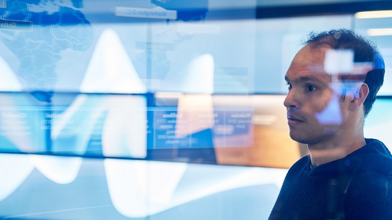 Ein Mann sitzt in einem Büro, der Hintergrund des Bildes ist komplett unscharf