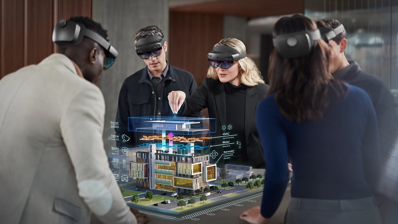 Mehrere Mitarbeiter tragen HoloLenses und arbeiten zusammen an einem virtuellen Geb&auml;udemodell