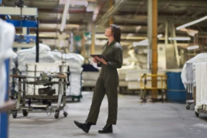 A manufacturing worker standing in a factory holding a tablet