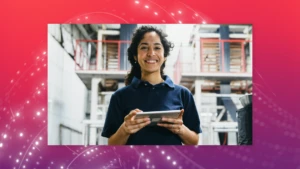 A woman stands in a warehouse holding a tablet.