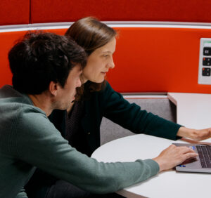 A woman and a man share a laptop computer.