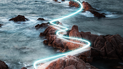 A glowing, winding path overlays a rocky coastal landscape, following the shoreline through the ocean.