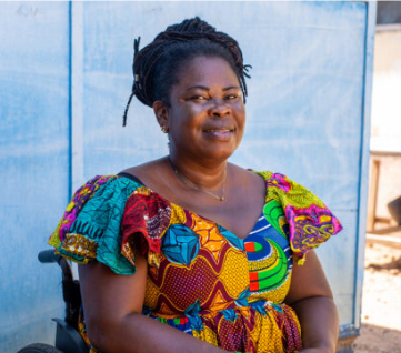 an African woman in a colorful dress smiling and looking at the camera