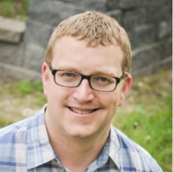 a man wearing glasses and smiling at the camera