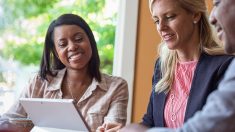 Image of three people sitting in front of an open computer smiling.