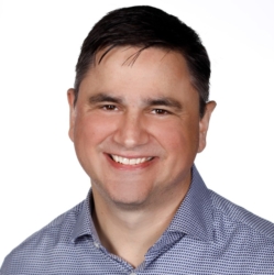 a man wearing glasses and smiling at the camera