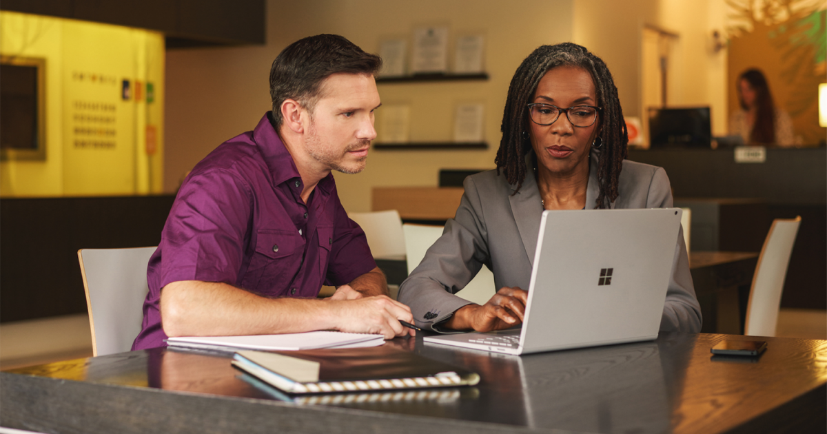 a group of people sitting at a table using a laptop computer