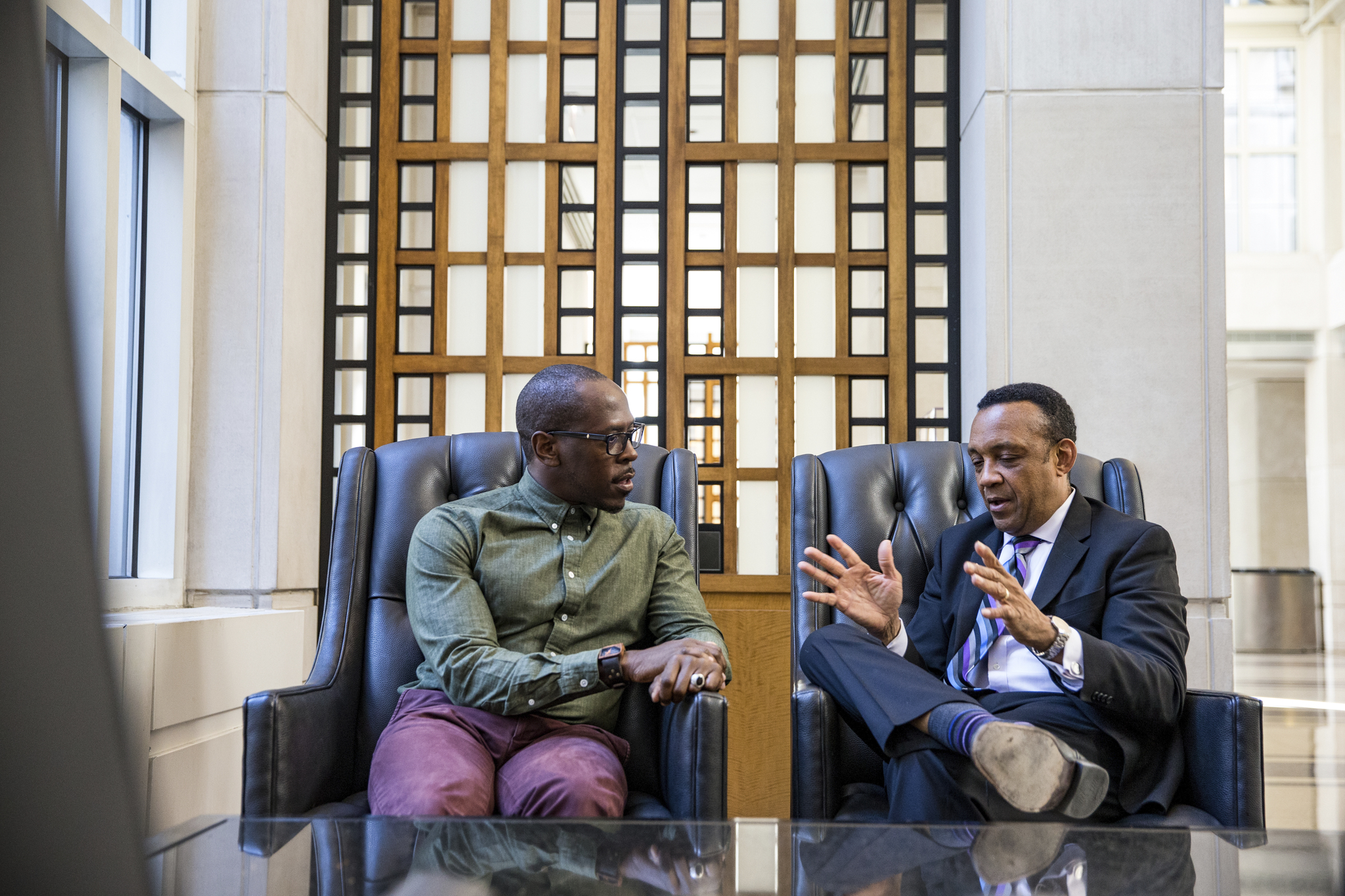 Two people sitting down talking to each other in a bright office setting.