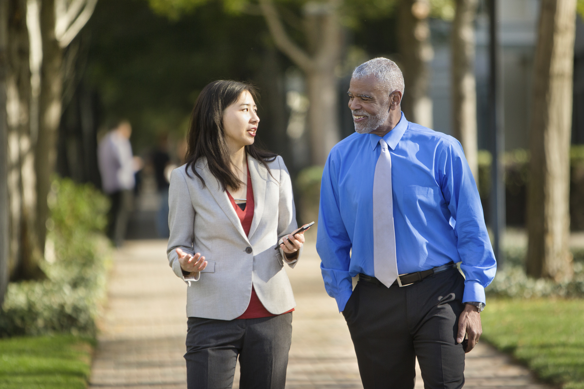 Two business people walking and talking outdoors.