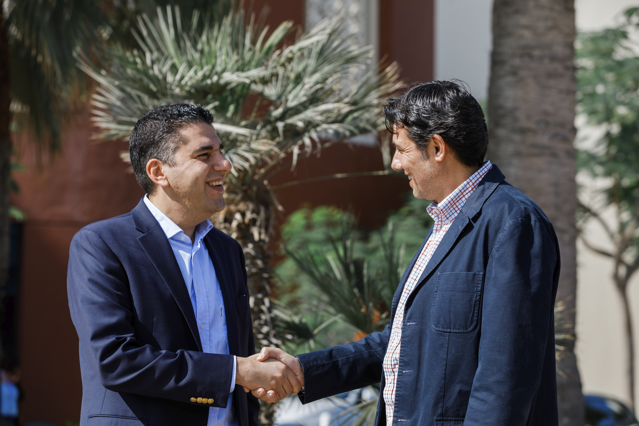 Two business people shaking hands and smiling.