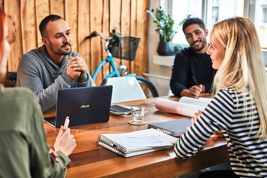 a group of people sitting at a table using a laptop