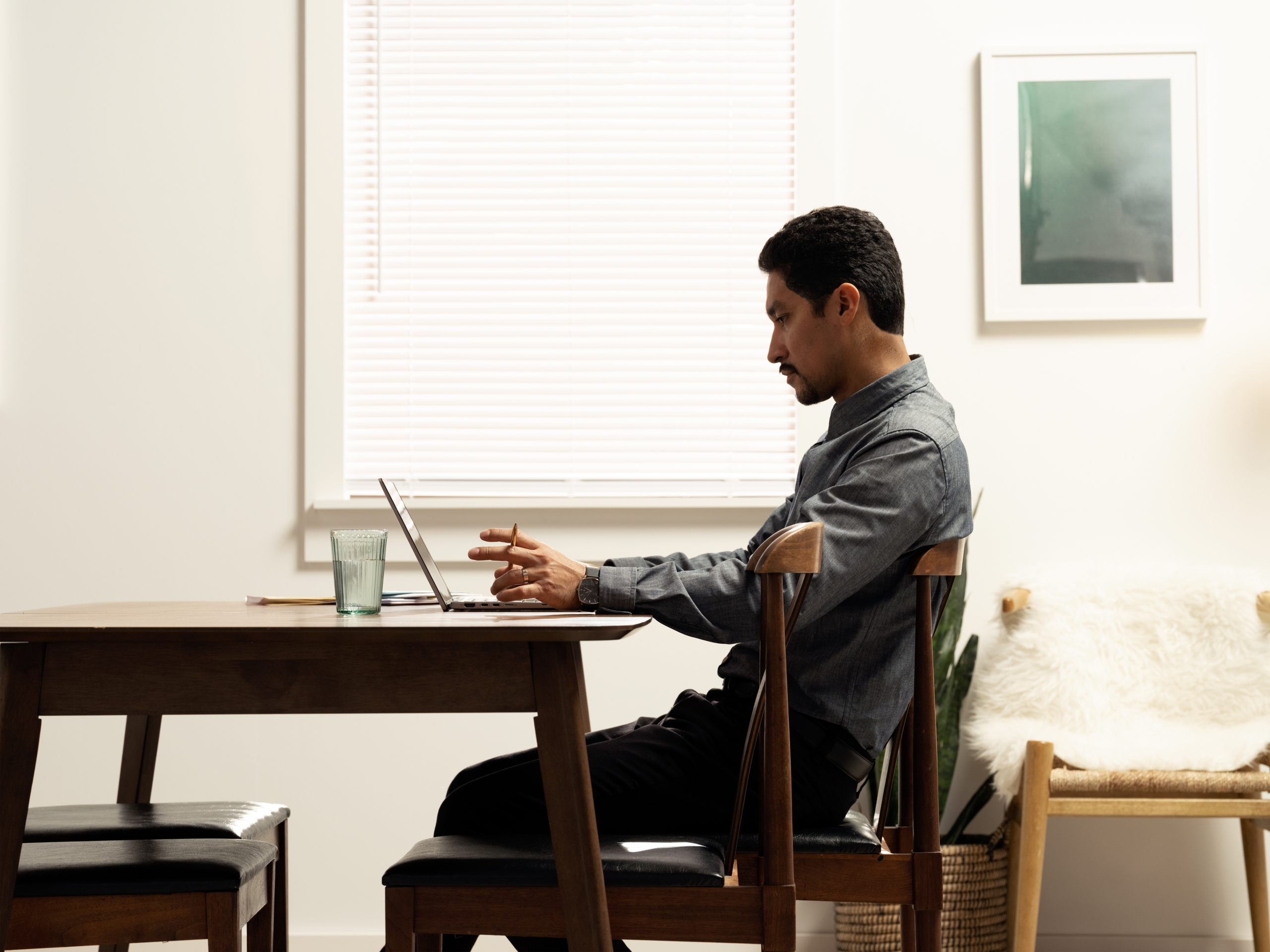 Side photo of man working at the dining room table with a Dell Latitude 7410. Keywords: remote work, remote working, work from home, working at home, home office, telecommuting, video conference, video call