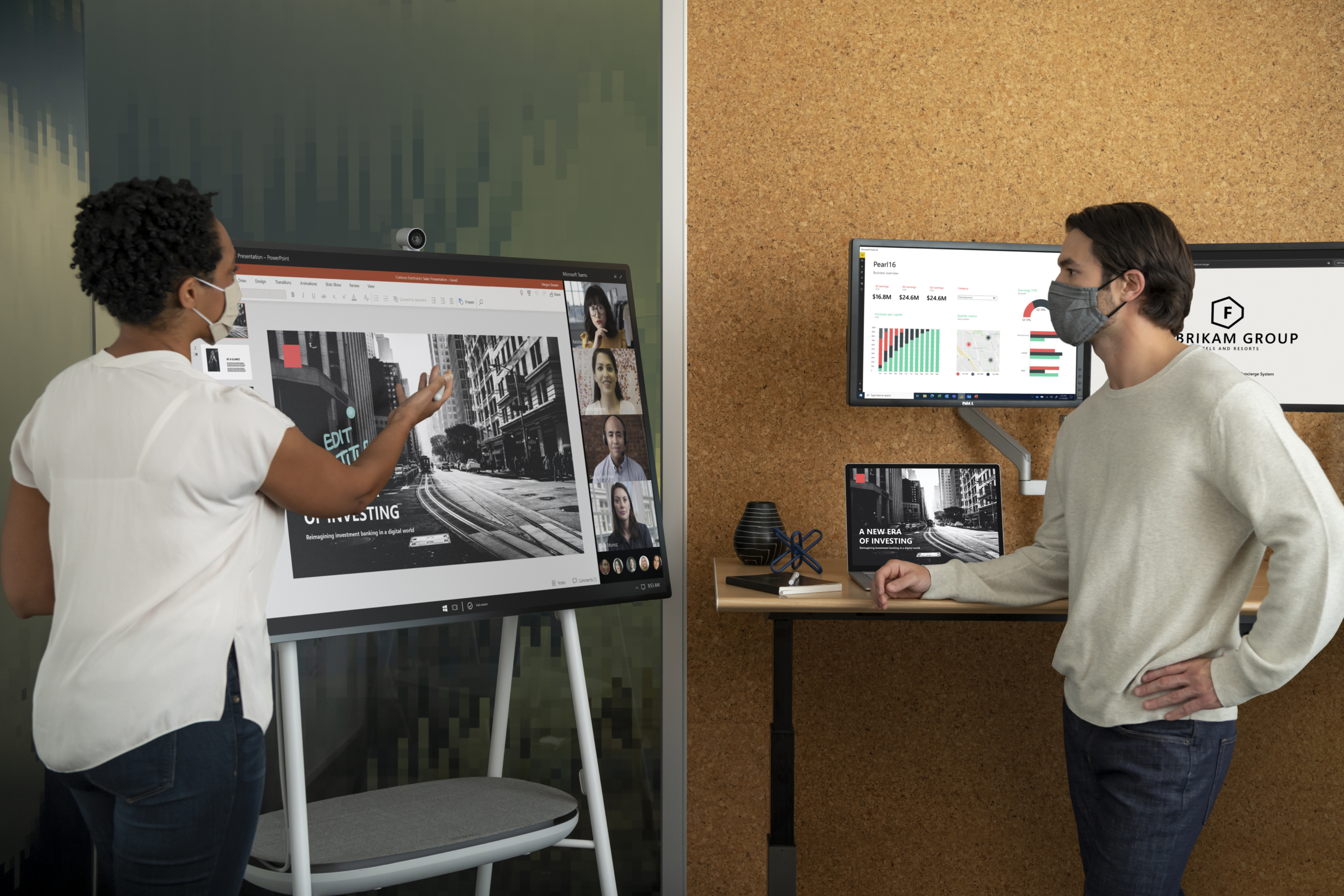 Two adults in masks collaborating on a PowerPoint presentation in an office while using a Microsoft Surface Hub 2S 50&rdquo; device during a Teams video call.
