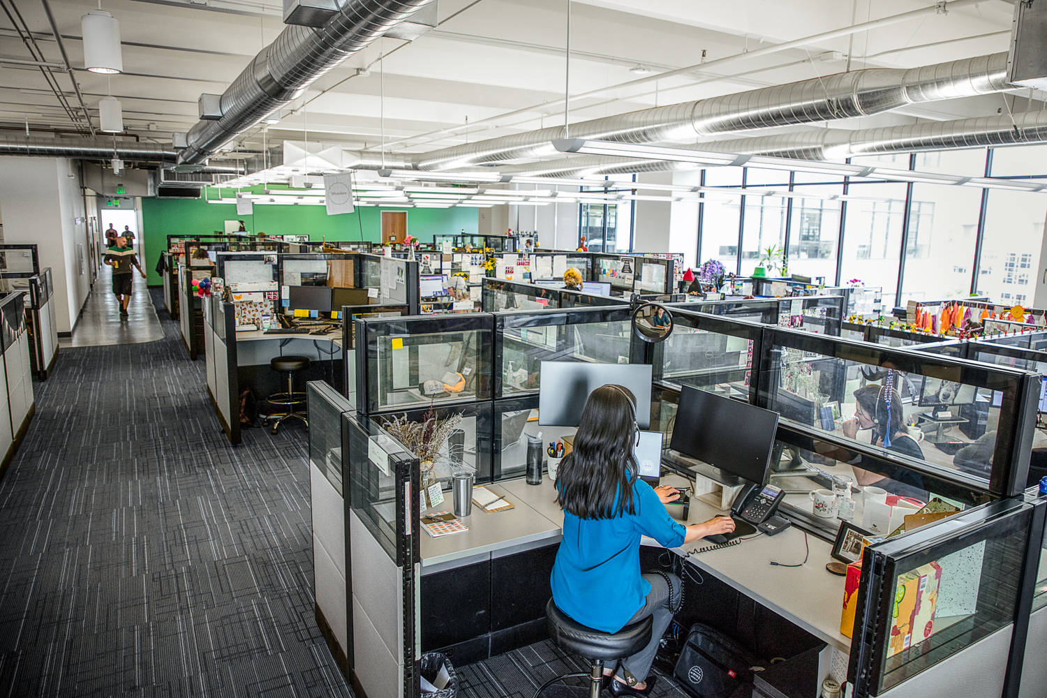 Call center employee in a cubicle, working alongside service AI agents