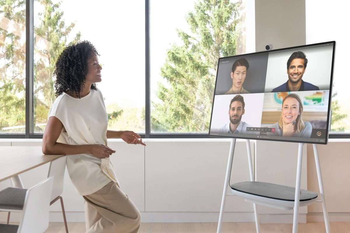 A person in an office along engaging with a Microsoft Teams calls with four faces on video.