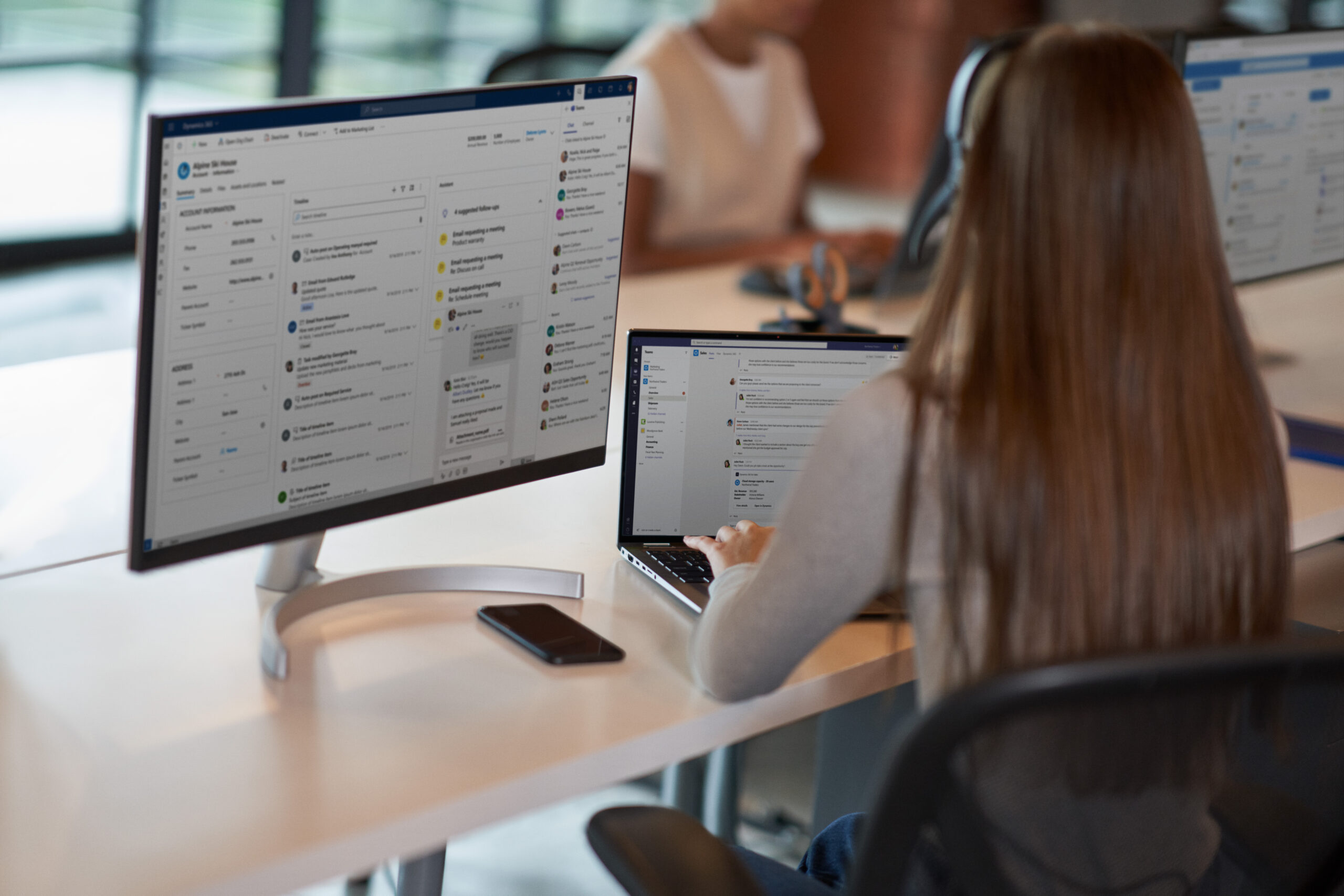 A woman sitting at a desk with two monitors, working on a customer service call.