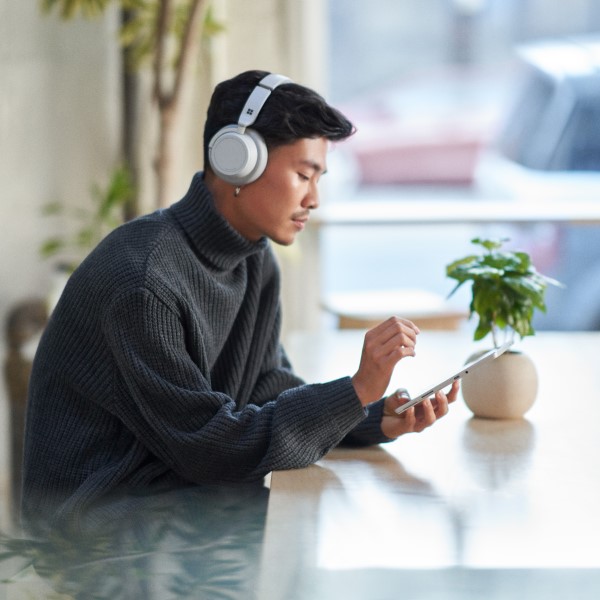 Customer using a tablet while wearing headphones and working securely remote from a caf&eacute;.