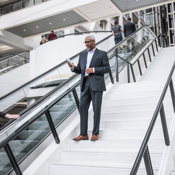A person in a suit, standing on stairs, looking at their phone.