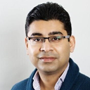 A man wearing glasses and a blue jacket