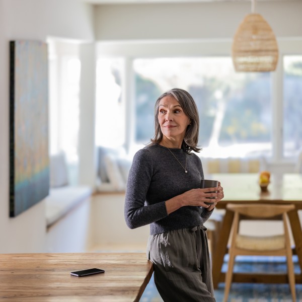 Portrait of woman holding a mug in a kitchen, leaning against a counter.