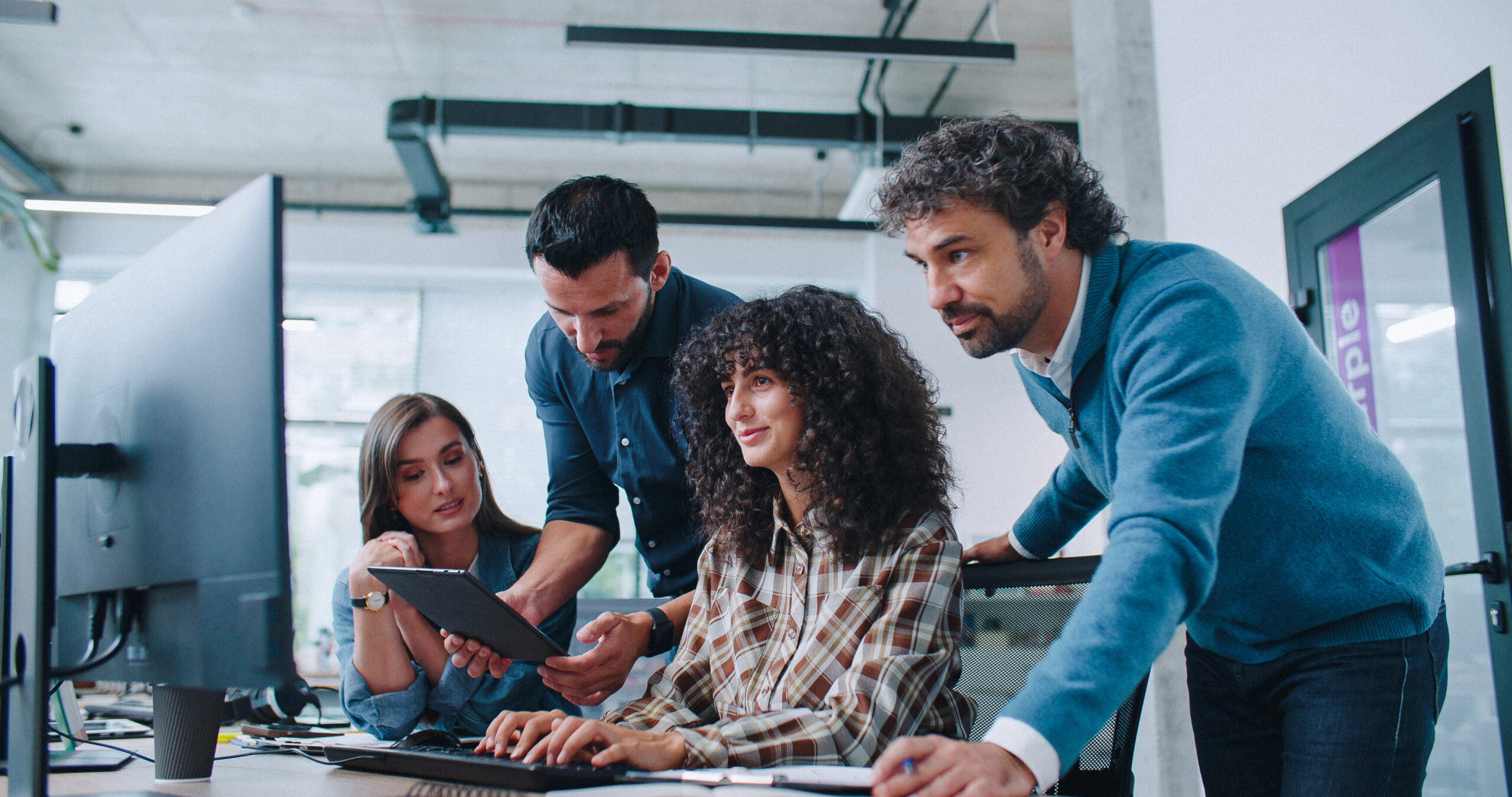 Group of smart coworkers intently looking at computer screen. People brainstorming about working plan or searching for solution to issue. Men and women positively communicating.