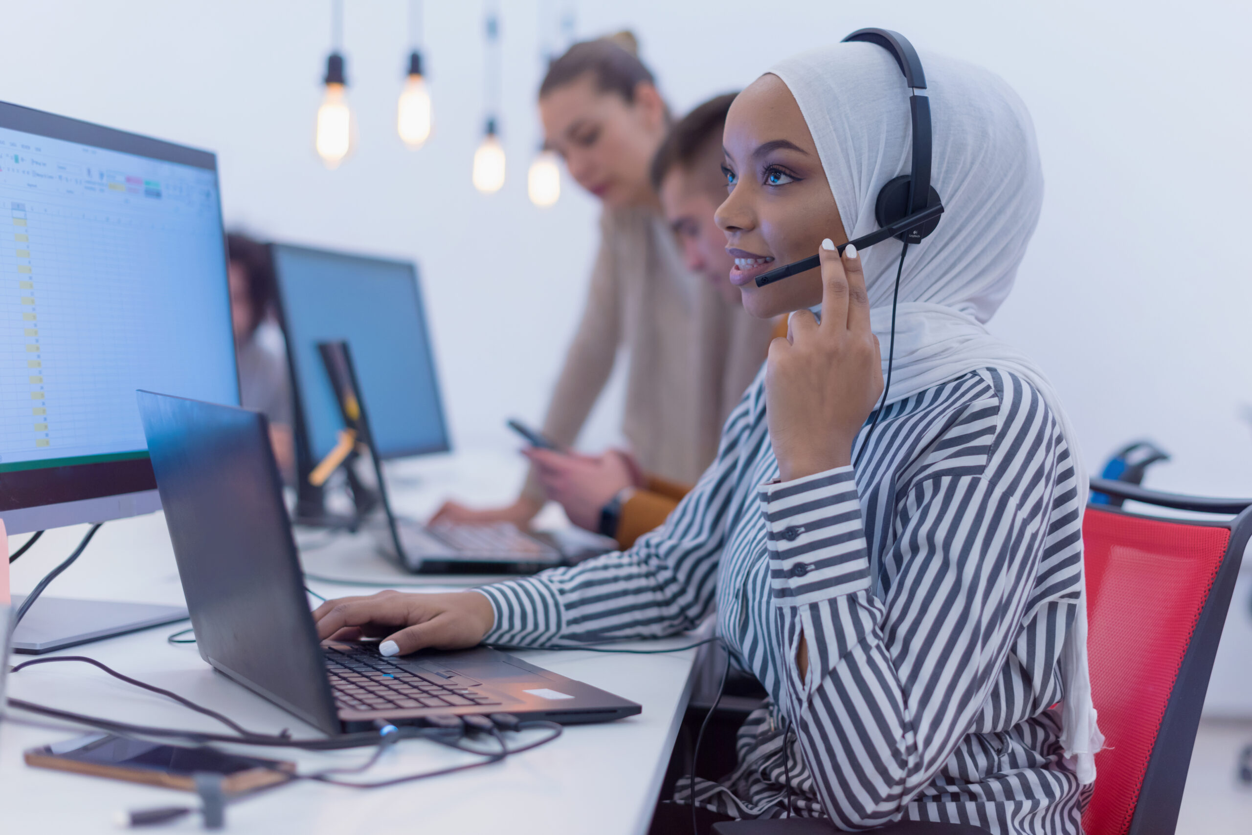 Female Customer Service Representative Answer Client's Questions in a Headset. Multi-Ethnic Team of Specialists.