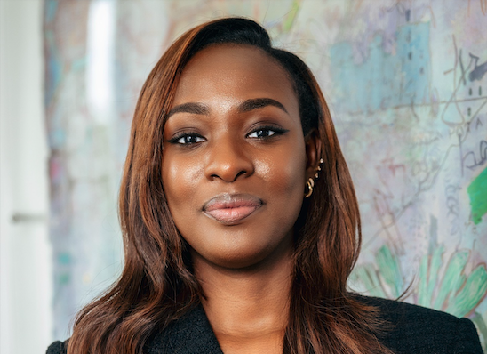 Professional headshot with long brown hair and a textured, colorful backdrop