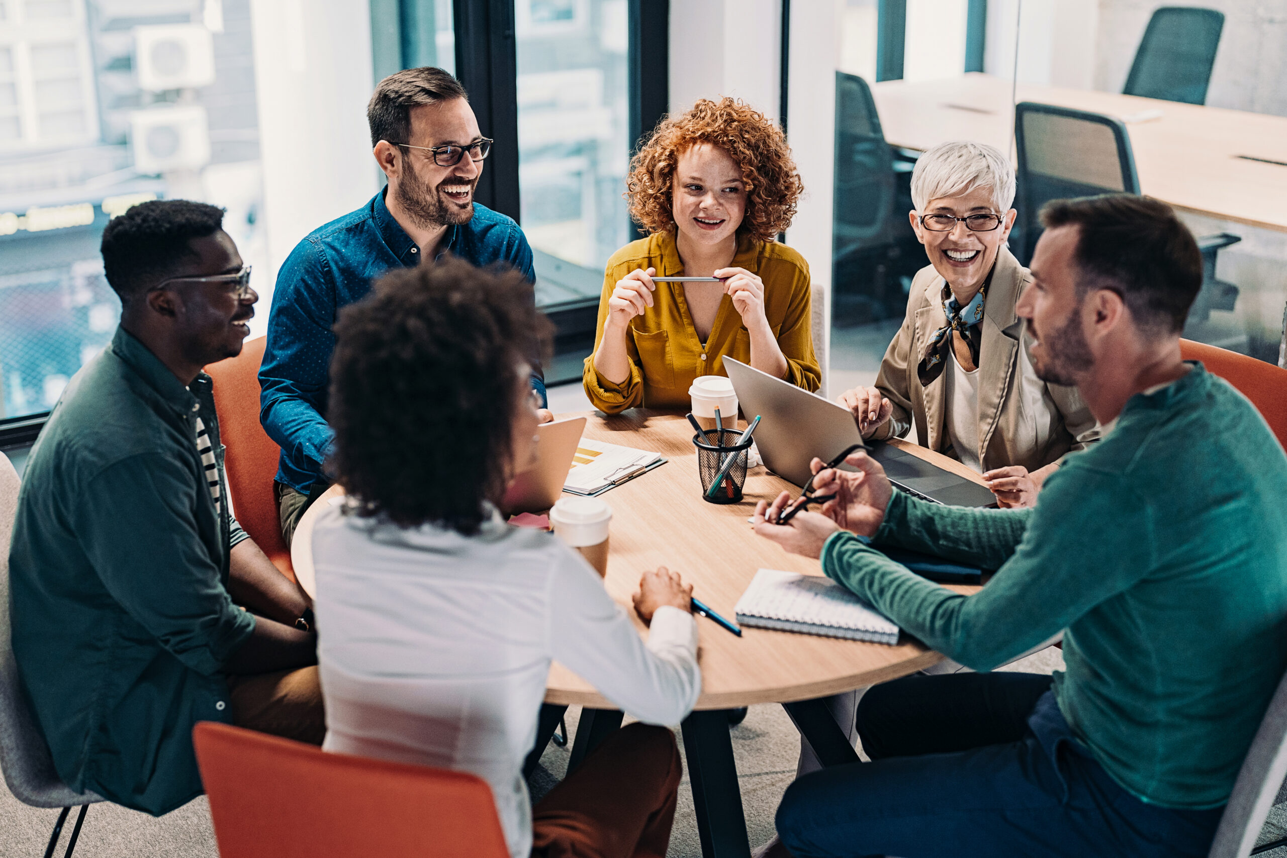 Group of business people having a meeting at a round conference table in a creative office.