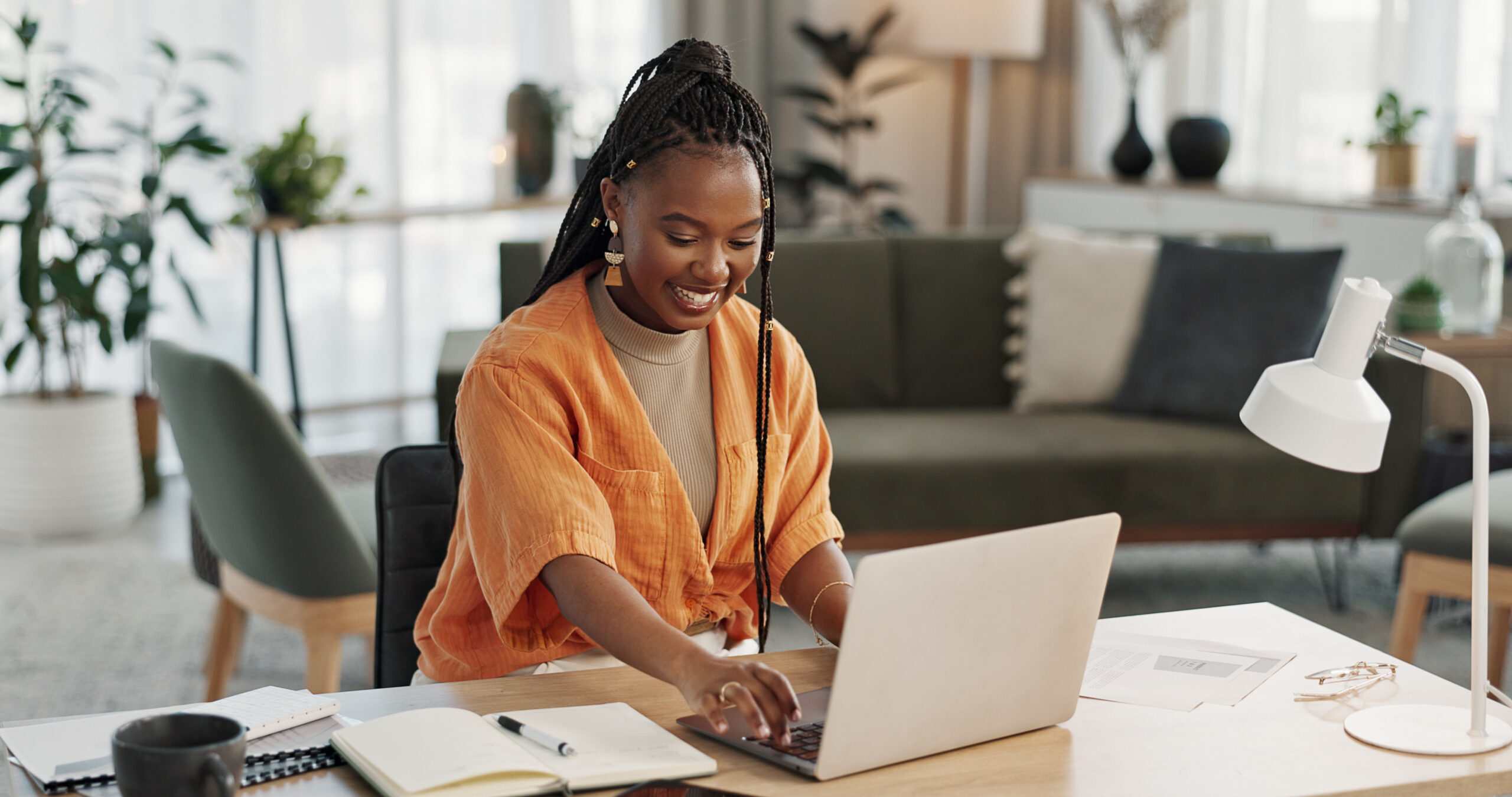 Black woman, typing in home office and laptop for research in remote work, social media or blog in apartment. Freelance girl at desk with computer writing email, website post and online chat in house.