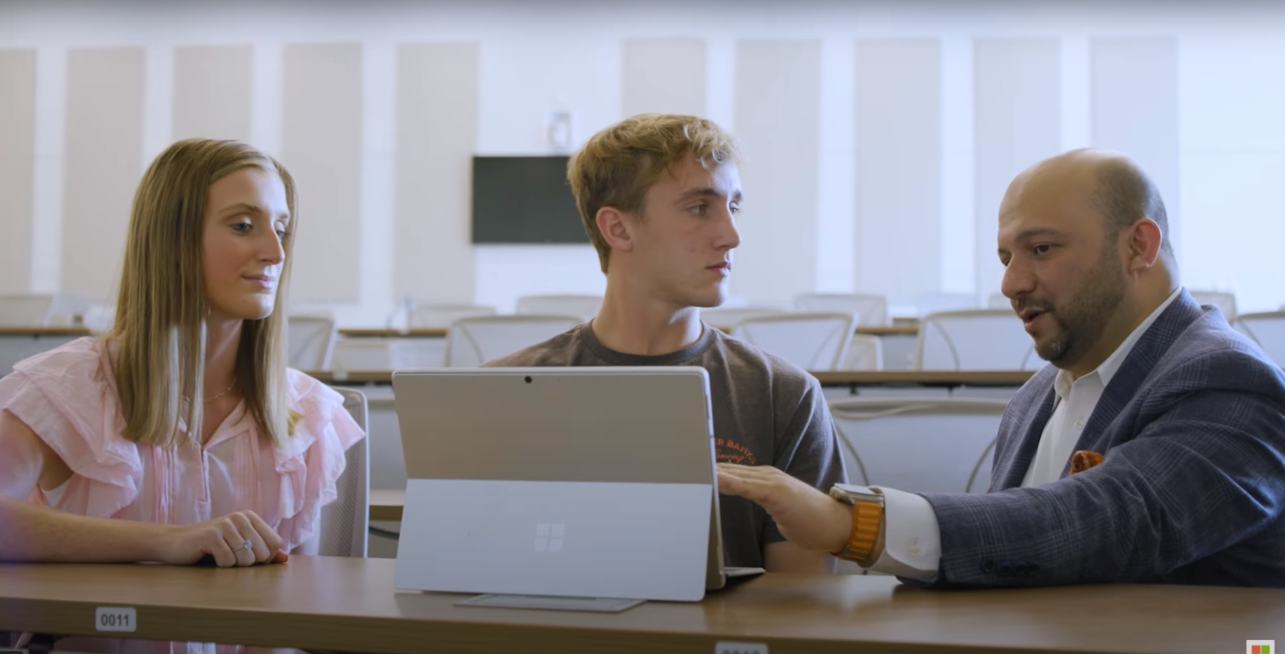 Two students and an educator collaborating in a university classroom.