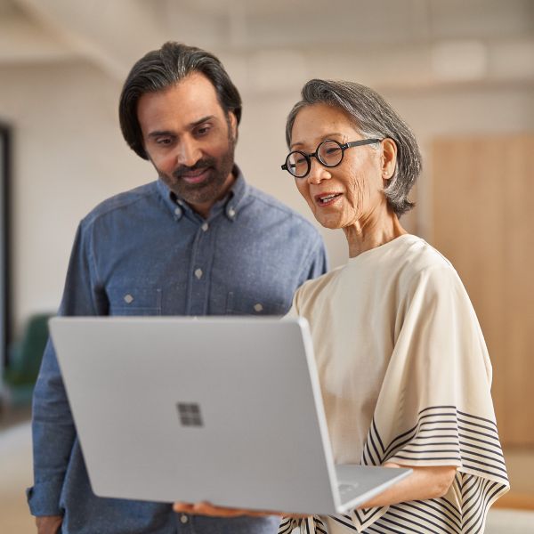 Two education leaders look at the screen of a laptop together.
