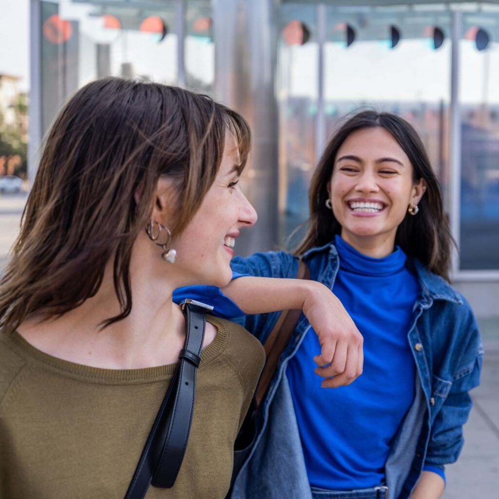 Two older students laughing together outside of a building.