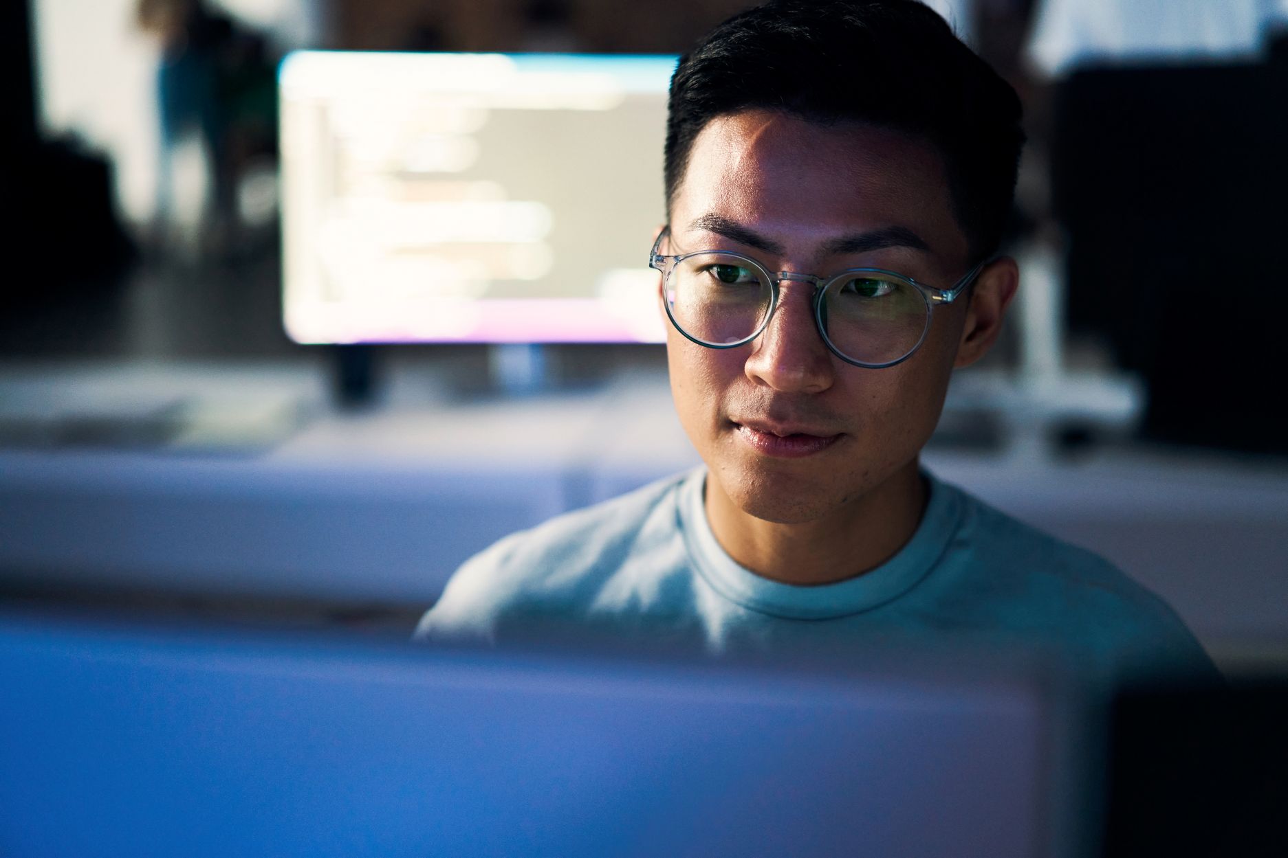 A person sitting at a desk and looking at a computer screen.