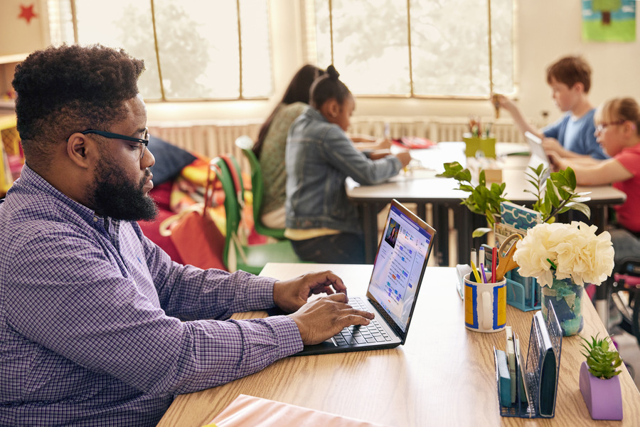 An educator in a classroom setting using a laptop showing Reading Progress.