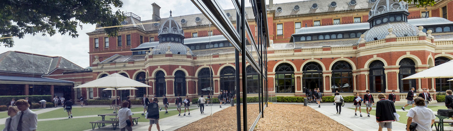 Exterior of a college campus with students walking and a reflection off windows.