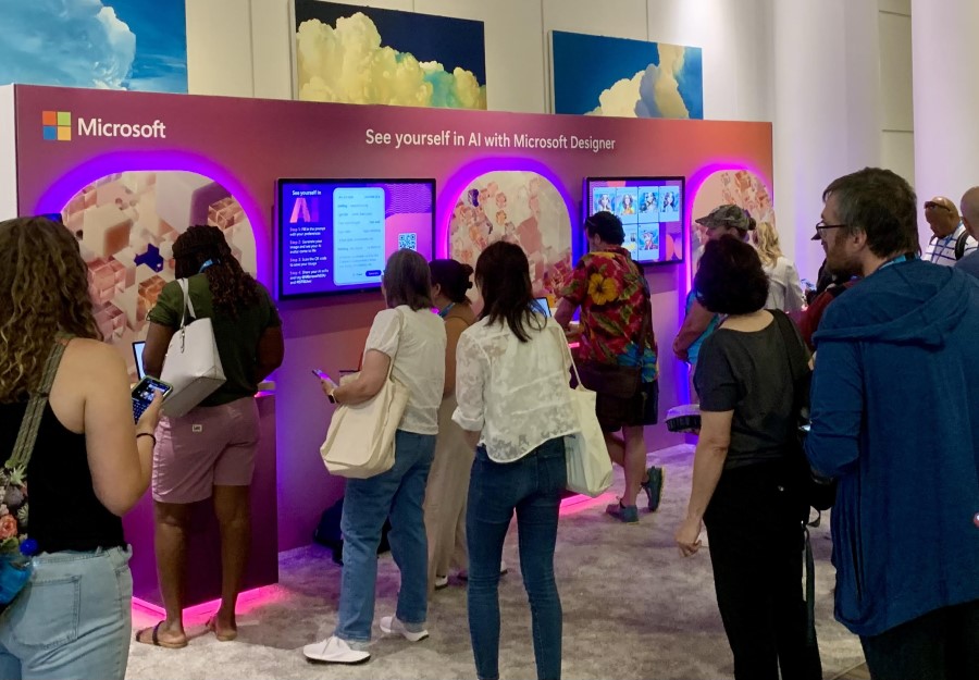 Decorative. Attendees lining up at a station with laptops at a booth on a conference floor.