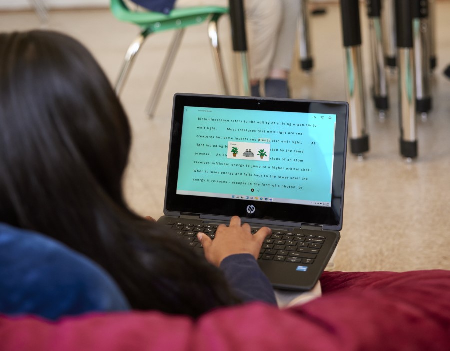 Decorative. A student sitting in a beanbag chair in a school classroom and working on a laptop.