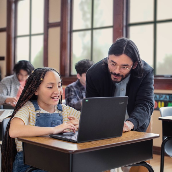 A teacher engaging with a student at the student’s desk in a school classroom.