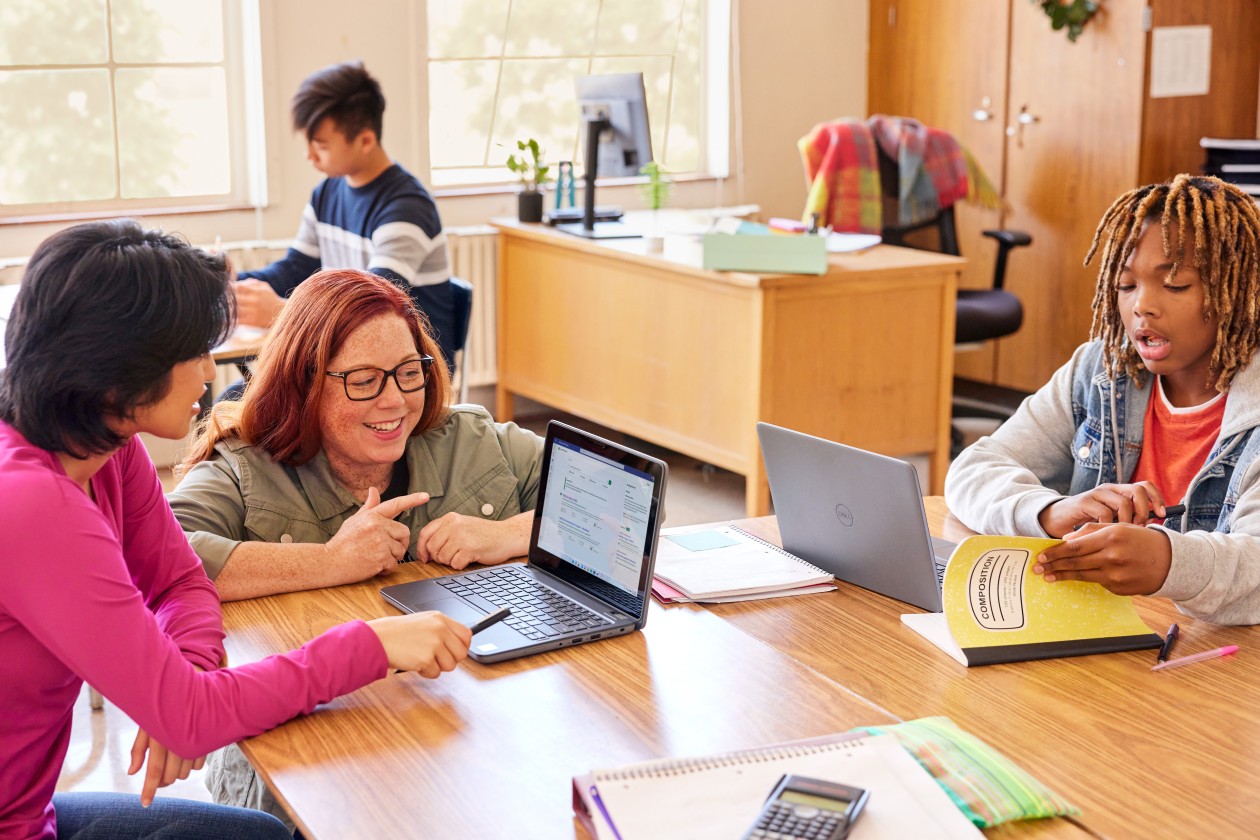 An educator engages with high school aged students at their desks in a school classroom.