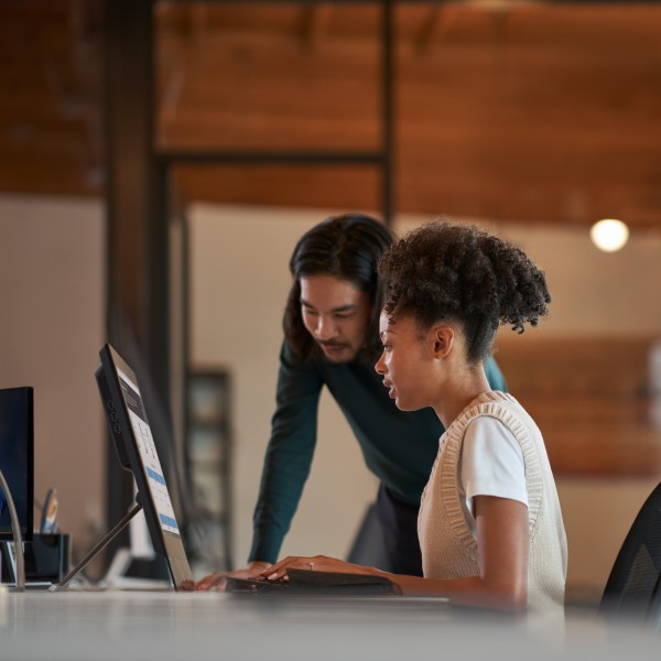 Two IT professionals working on a computer together in an office at an educational institution.