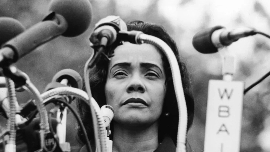 A close up of Coretta Scott King standing in front of a group of microphones.