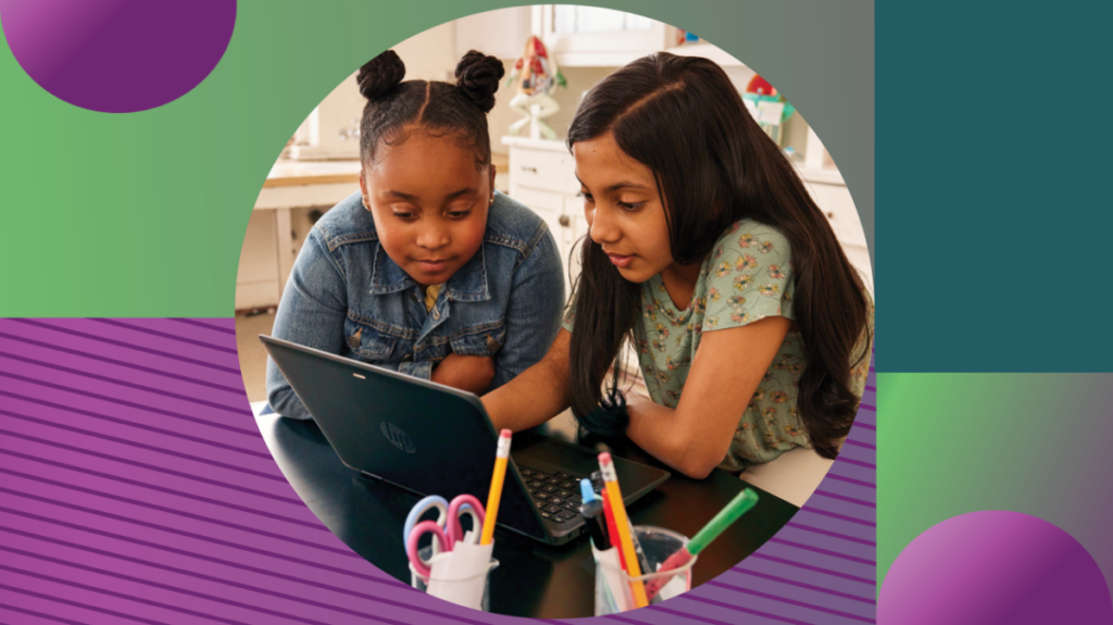 Two students working together on a laptop in a school classroom.