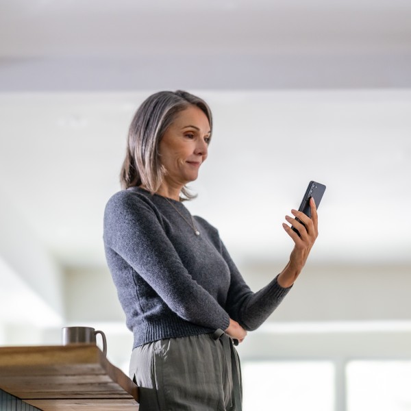 An education leader stands in a confident pose while looking at her phone.
