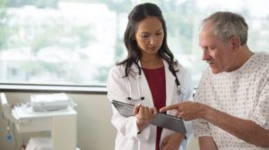 A doctor having a conversation with a patient and showing him a tablet