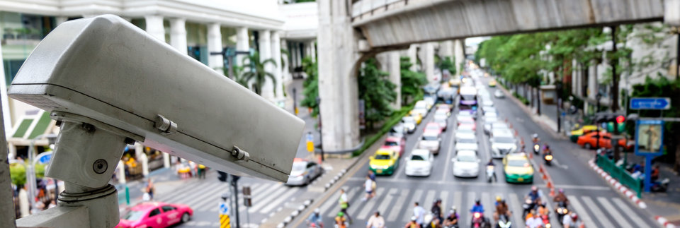 Close up CCTV security camera with blur of traffic jam