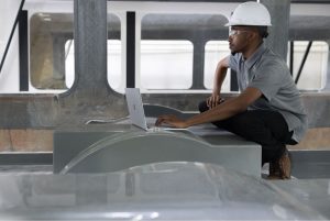 A man working on a laptop in a construction site.